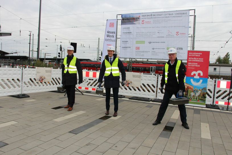 Mit dem Herausheben von Pflastersteinen leiten Holger Kelch (li.), Oberbürgermeister der Stadt Cottbus, Dr. Benjamin Grimm (Mitte), Staatssekretär in der Staatskanzlei Brandenburg, und Dr. Joachim Trettin (re.), Konzernbevollmächtigter der Deutschen Bahn für das Land Brandenburg, den Bau des Informationszentrums zum Strukturwandel in der Lausitz ein. Foto: sts