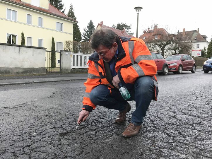 Reinhard Koettnitz zeigt typische Netzrisse auf der Caspar-David-Friedrich-Straße. Ende März soll sie in Schuss gebracht werden, der Bus dann wieder planmäßig verkehren. Foto: Schramm