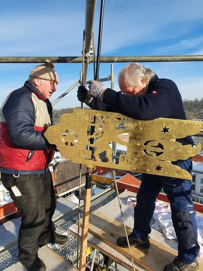 Schmiedemeister Merkel und Handwerksmeister Nennewitz montieren in 36 Metern Höhe die Wetterfahne. Fotos: IAB Brückner