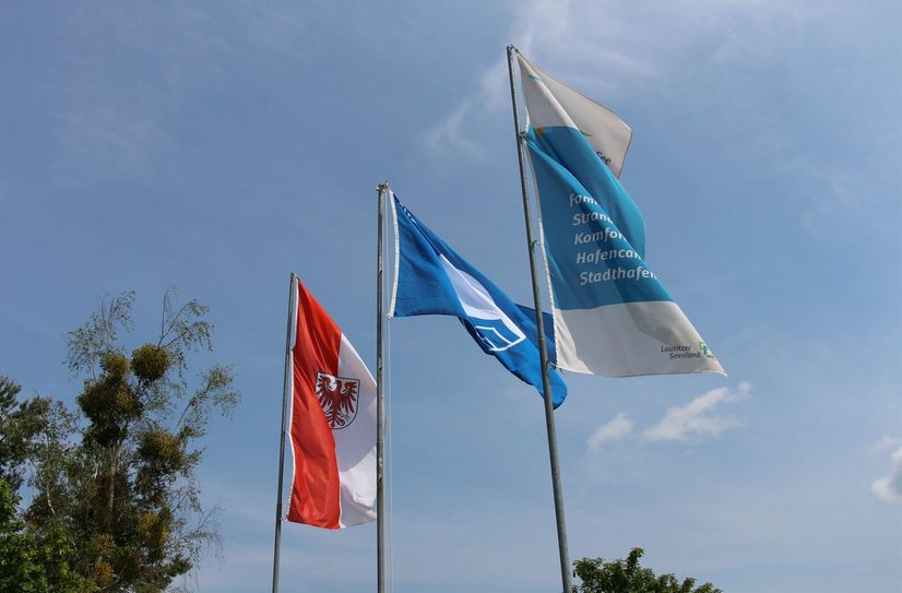 Wie damals 2019 weht auch im Jahr 2022 die »Blaue Flagge« (Mitte) am Senftenberger See am Strand von Großkoschen.