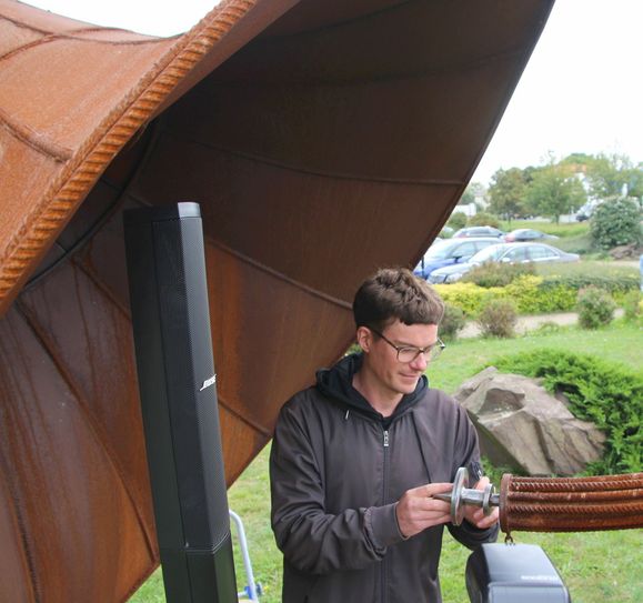 Metallkünstler Matthias Seifert passt das speziell angefertigte Mundstück an, damit der Musiker das Riesenhorn bespielen kann.