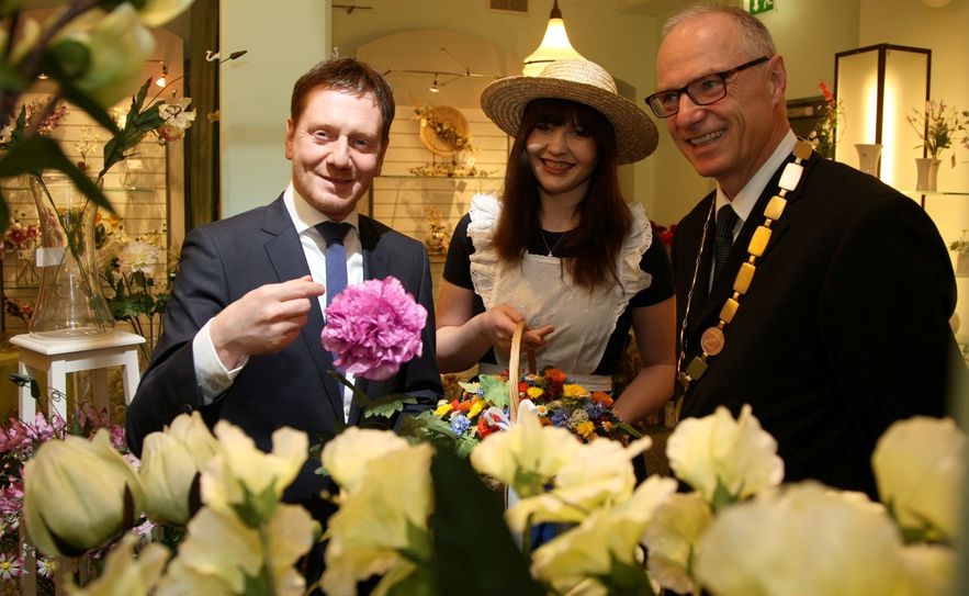 V.l.: Ministerpräsident Michael Kretschmer, Blumenmädchen (2015) Doreen Berger und das Sebnitzer Stadtoberhaupt Mike Ruckh im Haus der Deutschen Kunstblume. Foto: Daniel Förster