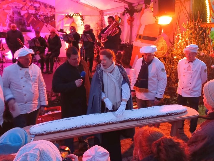 Oberbürgermeister Frank Höhme (2.v.l.) eröffnet gemeinsam mit dem Dresdner Stollenmädchen den Weihnachtsmarkt in der Röderstadt und testet den Riesenstollen.