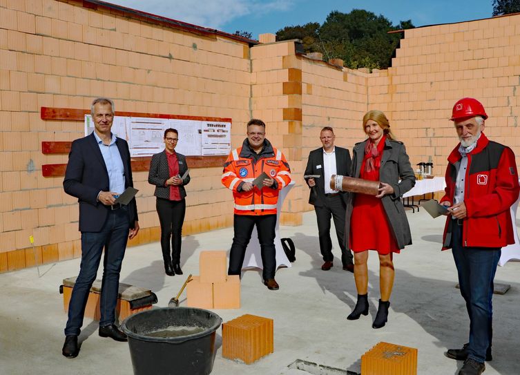 Vizelandrätin Susanne Rieckhof (2.v.r.) hat zusammen mit Bürgermeister Markus Mücke, DRK-Abteilungsleiterin Anja Thoß, Johanniter-Regionalvorstand Andreas Berger-Winkler, Ordnungsdezernent Stefan Klein und Planungsingenieur Matthias Bärmann (v.l.n.r) die Zeitkapsel im Grundstein einzementiert. Foto: Landkreis Dahme-Spreewald
