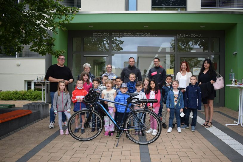 Gordon Stephan, Rowitha Nagel, Stephanie Gaumnitz, Steffen Blochwitz, Jan Schneiedwind, Kathrin Haug und Martina Theunert mit den Kindern der Klasse 2c der Europaschule Regine-Hildebrandt-Grundschule bei der Übergabe des AG-Leiter Fahrrades. Foto: asl