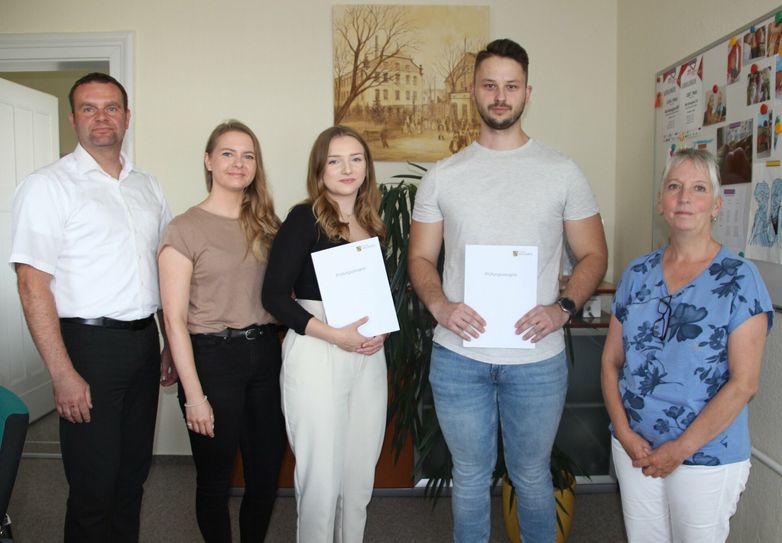 Bürgermeister Stefan Schneider, Ausbildungsbeauftragte Anna Sigmund, Auszubildende Maike Brückner und Alexander Trodler mit ihren Zeugnissen sowie Ausbildungsbeauftragte Petra Schölzel (v.l.n.r.).