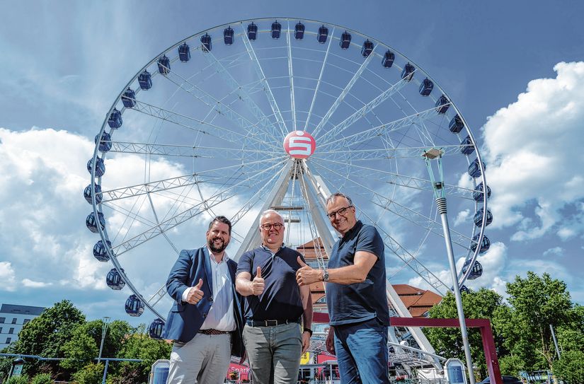 Henrik Oliver von Oehsen, Unternehmenssprecher der Ostsächsischen Sparkasse Dresden, Stadtfest-Organisator Frank Schröder und Schausteller Oscar Bruch jr. laden vor dem »Wheel of Vision« zum Stadtfest ein.