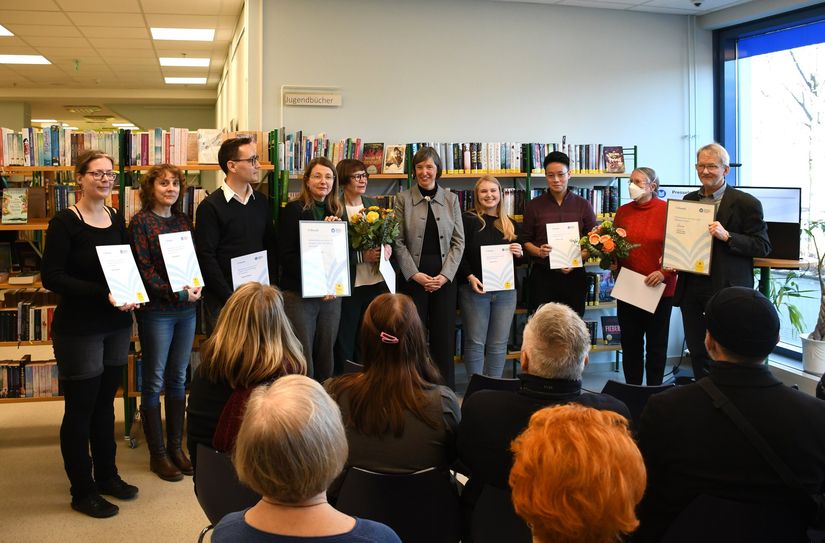 Verleihung des Titels »Bibliothek des Jahres 2024« durch Kulturbürgermeisterin Annekatrin Klepsch (4.v.li.), Marit Kunis (Direktorin Städtische Bibliotheken, 5.v.re.) und Roman Rabe (Bibliothekarischer Fachdirektor, re.).