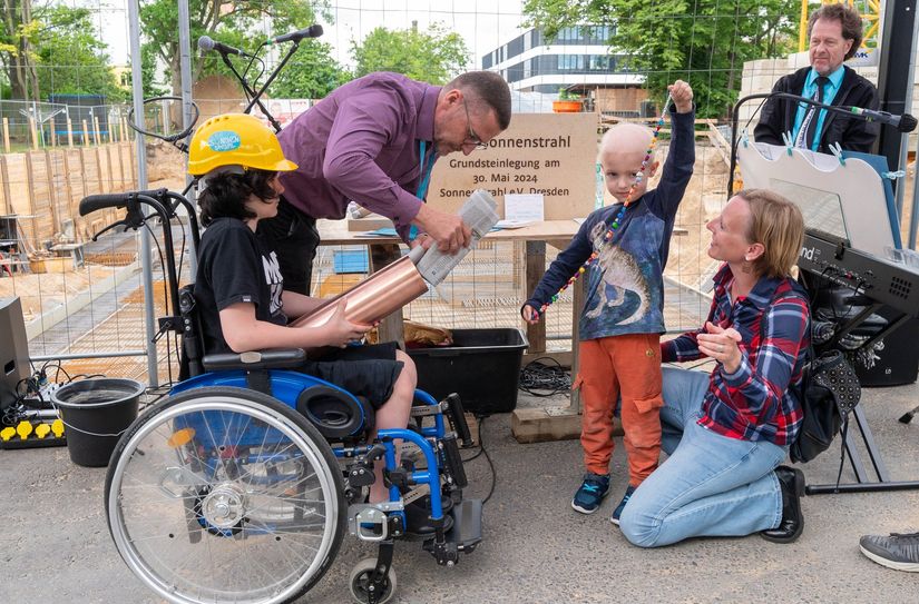 Zwei betroffene Familien mit ihren Kindern füllten die Zeitkapsel mit Bildern aus der Kunsttherapie, einer Mutperlenkette und verschiedenen Zeitdokumenten.