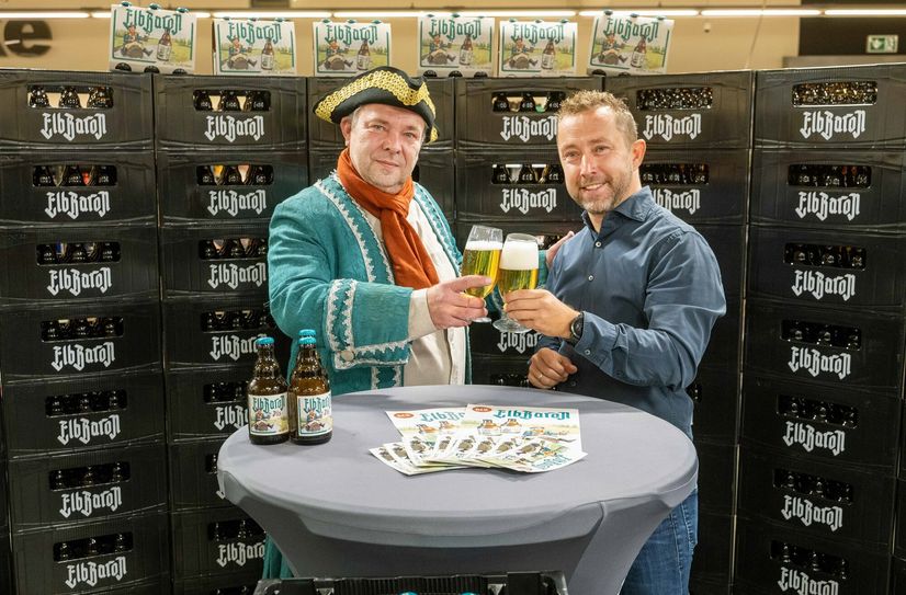 John Scheller (re., Marktleiter Edeka Hamburger Straße) stößt mit dem Elbbaron an.