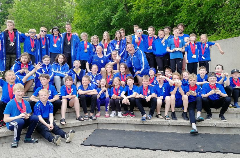 57 Riesaer Schwimmer, ihre Trainer und Betreuer freuen sich über den erkämpften Mannschaftspokal beim großen Schwimmfest in Herford.