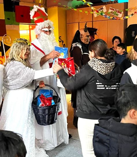 Der Nikolaus mit dem Engel übergibt Geschenke an die Kinder.