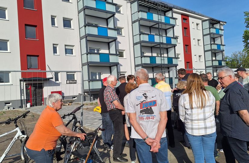 Eine Sonneninsel mitten in Senftenberg? Anja Rost, Teamleiterin Wohnen bei der KWG, erklärt den Stadtteilspaziergängern, was es damit auf sich hat. Noch bekommt die Sonneninsel in der Johannes-R.-Becher-Straße 7 bis 11 ihren letzten Schliff, ab Juli rollen hier die Möbelwagen vor.
