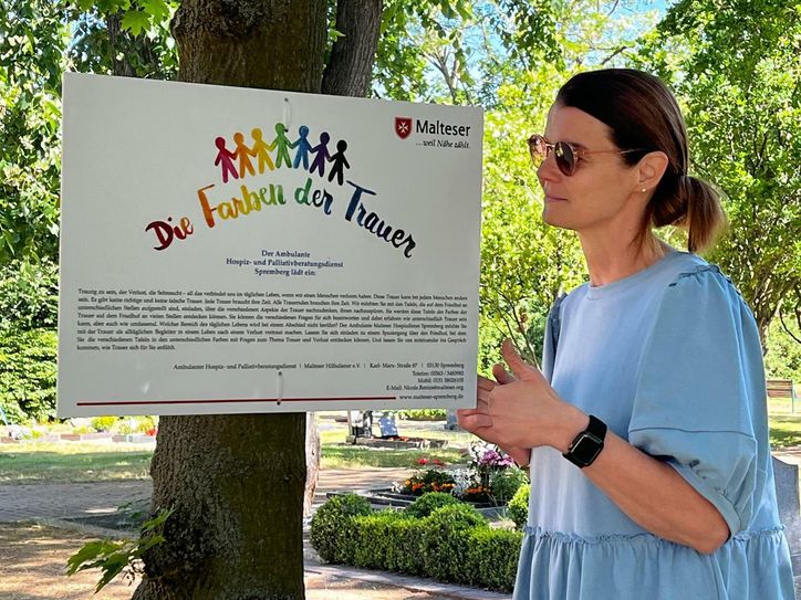 Nicole Benics, Leitende Koordinatorin Malteser Hospizdienst Spremberg, verweist auf die Ausstellung, die auf dem Friedhof Drebkau aufgebaut ist.