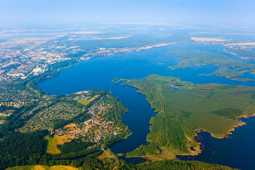 Der Senftenberger See aus der Vogelperspektive. Auf einem rund drei Kilometer langen Abschnitt, links und rechts vom Hafen (oben Mitte), zwischen Gaumensegel und Buchwalder Strand, soll eine Art grünes Band in Seenähe entstehen. Foto: Zweckverband LSB/Andreas Franke