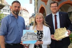 Kulturservice-Prokurist Gerd Weise, Kulturservice- Geschäftsführerin Maria Schulz und Bürgermeister Benedikt M. Hummel präsentieren das Motiv des Altstadtfest-Pins 2023.