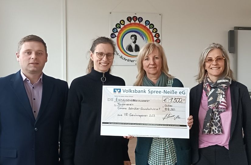 René Hammel (l.) übergibt den Spendenscheck aus dem VR-Gewinnsparen an Frau Rauhut, Frau Kleindienst und Frau Türke (v.l.) vom Förderverein der Corona-Schröter Grundschule.