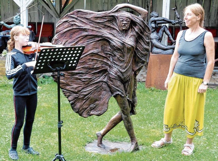 Jolina Große begleitet die Doberluger Künstlerin Catrin Große, hier nebeneiner  ihrer Monumentalplastiken, auf der Violine.
