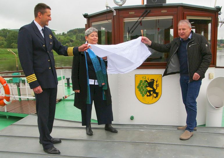 Kapitän Jan Schröter, Geschäftsführerin der Sächsischen Dampfschifffahrt, Karin Hildebrand, und Bürgermeister Gert Barthold enthüllen das Ortswappen am Raddampfer »Diesbar«.Foto:  Farrar