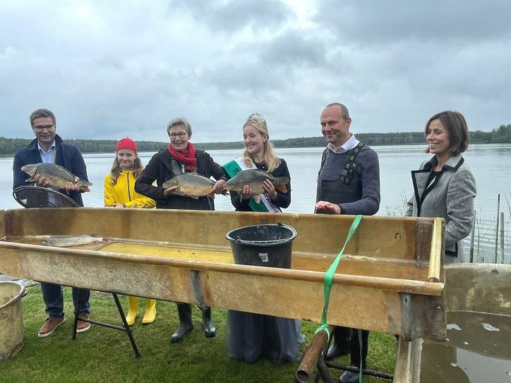Patricia Wissel MdL, Umweltminister Wolfram Günther, Sächsische Fischkönigin Charlotte Opitz, Referentin im Umweltministerium Ulrike Weniger, ‚Fischers Franzi&apos; und Geschäftsführer des Landesfischereiverbandes Andreas Stummer (v.r.n.l.) bei der Eröffnung der Sächsischen Karpfensaison und der 21. Lausitzer Fischwochen am Großteich in Deutschbaselitz.