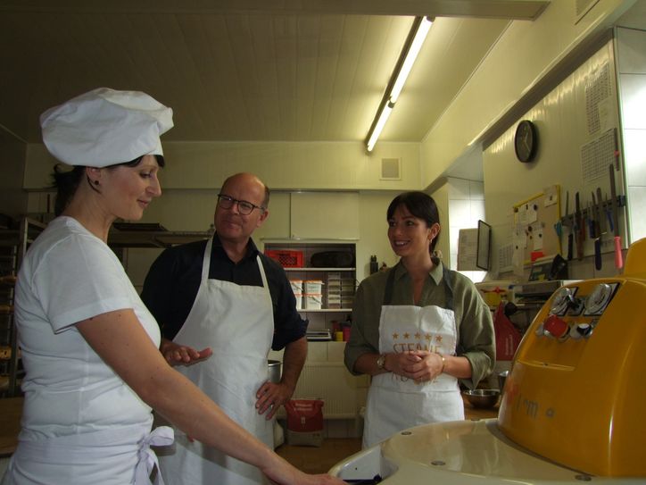 Bäckermeisterin Therese Martin erklärt Oliver Schenk und Elaine Jentsch, worauf es beim Stollenbacken ankommt.