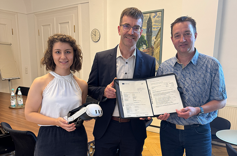 Christoph Koban erhielt von Jörg Szewcyk und Schulamtsmitarbeiterin Laura Seiffert den bewilligten Fördermittelbescheid für das BSZ Kamenz. Laura Seiffert brachte zudem eine VR-Brille mit, die - mit weiteren Exemplaren - künftig ebenfalls am BSZ zum Einsatz kommen wird.