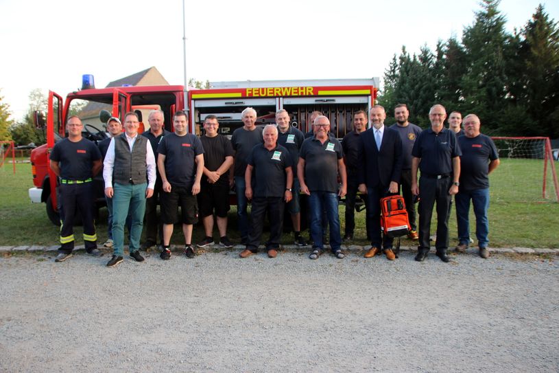 Die Kameraden der Freiwilligen Feuerwehr Gleina sowie der Bürgermeister Matthias Seidel (links) und der CDU-Landtagsabgeordnete Marko Schiemann stehen vor dem Feuerwehrfahrzeug.
