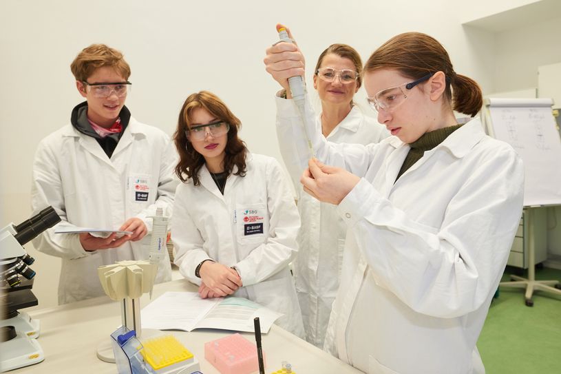 Anne Francken, kafmännische Geschäftsführerin der BASF Schwarzheide GmbH, schaut Schülern beim Experimentieren über die Schulter.