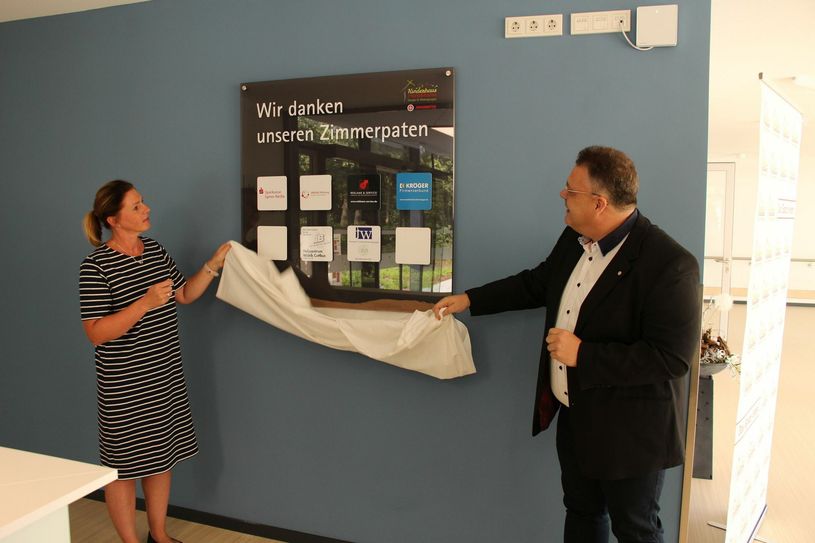 Daniela Konzack (li.), Einrichtungskleiterin des Kinderhauses »Pusteblume«, und Andreas Berger-Winkler aus dem Regionalvorstand der Südbrandenburger Johanniter, enthüllen die erste Tafel der Zimmerpaten. Foto: sts