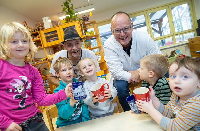 Cartoonist Kümmel (links) und Apotheker Heiko Neumann besuchen die Gruppe 1 im Kindergarten Pusteblume. Im vergangenen Jahr gab’s die große rote Tasse auf dem Weihnachtsmarkt. Diesmal ist es die neue, blaue Tasse.
