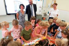 Klassenlehrerin Simone Müller, Staatsminister Christian Piwarz und Schulleiterin Heike Peter (v.l.n.r.) sehen beim Auspacken der vom Minister mitgebrachten Zuckertüte zu. Die Jungen und Mädchen der Klasse 1a freuen sich über das Geschenk.
 Foto: Matthias Stark