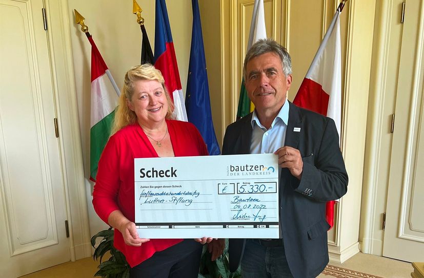 Landrat Michael Harig überreicht den symbolischen Scheck an Margitta Luttner.