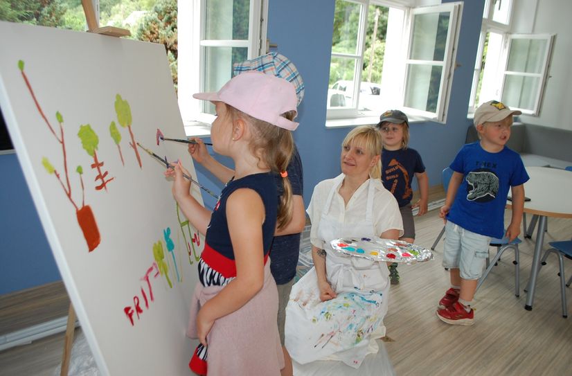 Künstlerin Jana Pischang (3.v.re.) bemalt mit den Kita-Kindern eine Mitmach-Leinwand für die Kita.