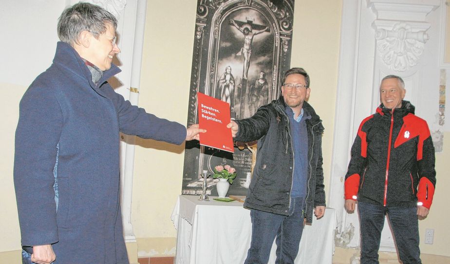 Mit dem nötigen Abstand aber viel Wärme im Herzen übergibt Patricia Werner, Geschäftsführerin der Ostdeutschen Sparkassenstiftung, den Förderbescheid für die Restauration der Kapellenmalerei im Hirschsteiner Schloss an Bürgermeister Conrad Seifert. Auch Rainer Schikatzky (r.) freut sich über die fünfstellige Förderung für ein Schloss im Landkreis Meißen.
