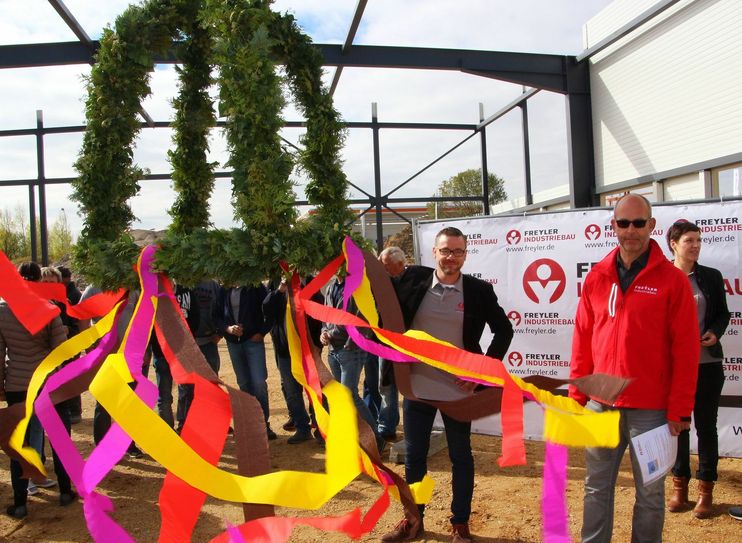 Andreas Hetke und Projektleiter Steffen Engert vom Freyler Industriebau bringen die Richtkrone für den Neubau des Sanitätshauses Hetke & Sengewitz in Position.  Foto: Farrar