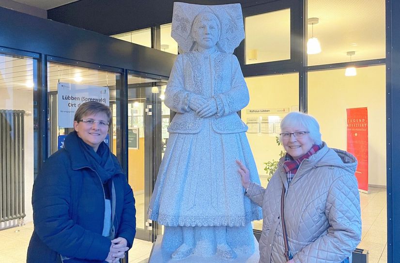 Karola Ziemainz (li.) und Erika Fiedler (re.) an der Granitfigur einer Spreewaldfrau. Die Figur ist von zwei Menschen inspiriert: Die Tracht der Statur ist von der Wendin Marga Morgenstern. Das Gesicht zeigt Frieda Völkner.
