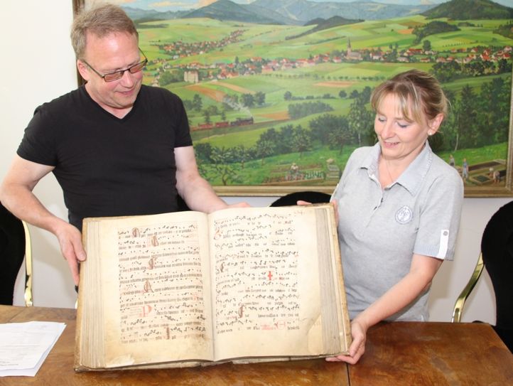 Dirk Keil, Burgwart auf dem Berg Oybin und Gästeführerin Simone Richter zeigen einen der beiden Schätze, das Gesangbuch in Pergamenthandschrift. Foto: Keil