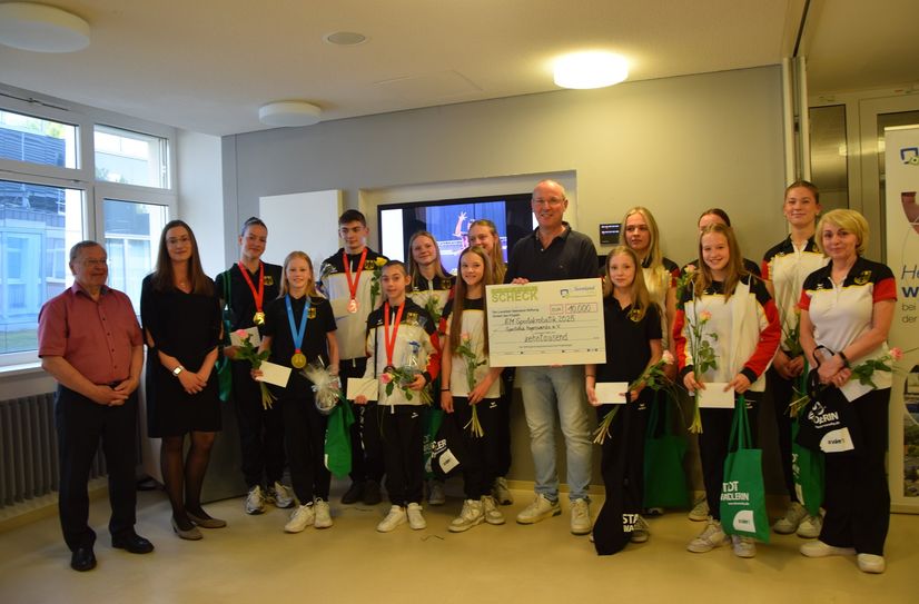 Johanna Schöne, Nona Kara, Lewis Gröllich und Milena Lalkov (mit Medaillen) und die anderen EM-Teilnehmer freuen sich über ihr gutes Abschneiden und die Spende der Lausitzer Seenland Stiftung für den gesamten Sportclub, die Steffen Markgraf in den Händen hält.