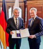 Der Vereinsvorsitzende des Zeithainer Reit- und Fahrvereins, Joachim Schreiber (l.),  erhält den Verdienstorden der Bundesrepublik aus den Händen von Ministerpräsident Michael Kretschmer.