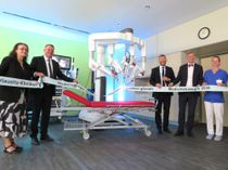 Der neue OP-Roboter da Vinci beim symbolischen Durchschnitt des Bandes, welches von Staatssekretärin Dagmar Neukirch, Landrat Udo Witschas, Klinik-Greschäftsführer Jörg Scharfenberg, Staatskanzleichef Dr. Andreas Handschuh und der OP-Schwester Lisa Winter gehalten wird (v.l.n.r.).