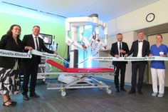 Der neue OP-Roboter da Vinci beim symbolischen Durchschnitt des Bandes, welches von Staatssekretärin Dagmar Neukirch, Landrat Udo Witschas, Klinik-Greschäftsführer Jörg Scharfenberg, Staatskanzleichef Dr. Andreas Handschuh und der OP-Schwester Lisa Winter gehalten wird (v.l.n.r.).
