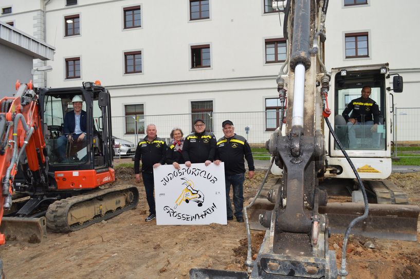 Großenhains Oberbürgermeister Dr. Sven Mißbach (links im roten Bagger), der stellvertretende Vorsitzende des Judosportclubs Steffen Klemt, Schatzmeisterin Heidi Minsel, Schriftführer Stefan Schneider, Präsident Dieter König sowie der Vorsitzende Arlindo Freyer (im weißen Bagger) beim symbolischen ersten Baggerhub für die neue Judohalle an der Nordseite der Rödertal Sporthalle.