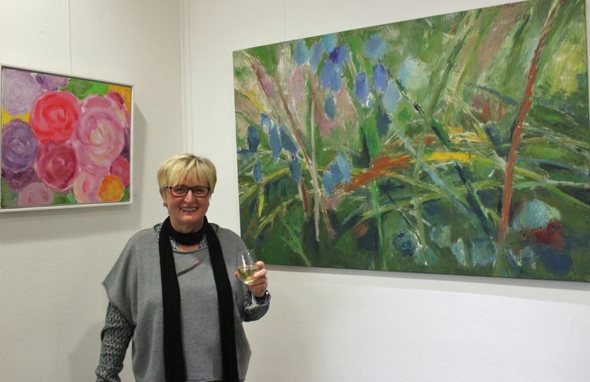 Rosemarie Böhmchen vor Malarbeiten mit pflanzlichen Motiven.