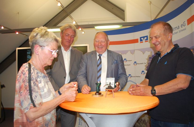 "Feuerprobe" des Caspar-David-Friedrich-Räuchermanns. Schöpferin der Figur Eva Beyer zündet im Beisein von Hauke Haensel (Vorstandsvorsitzender Volksbank eG), dem Ideengeber Klaus Brähmig MdB aD und Prof. Thomas Gischke (Aufsichtsratsvorsitzender Volksbank eG) (v.l.n.r.) eine Räucherkerze an.